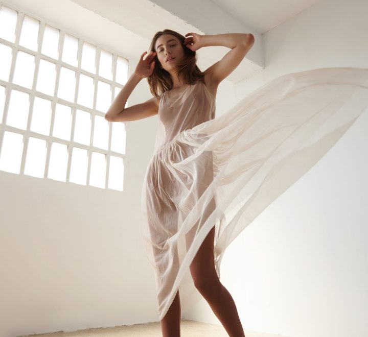 woman is dancing in ballerina's dress in light loft with industrial window